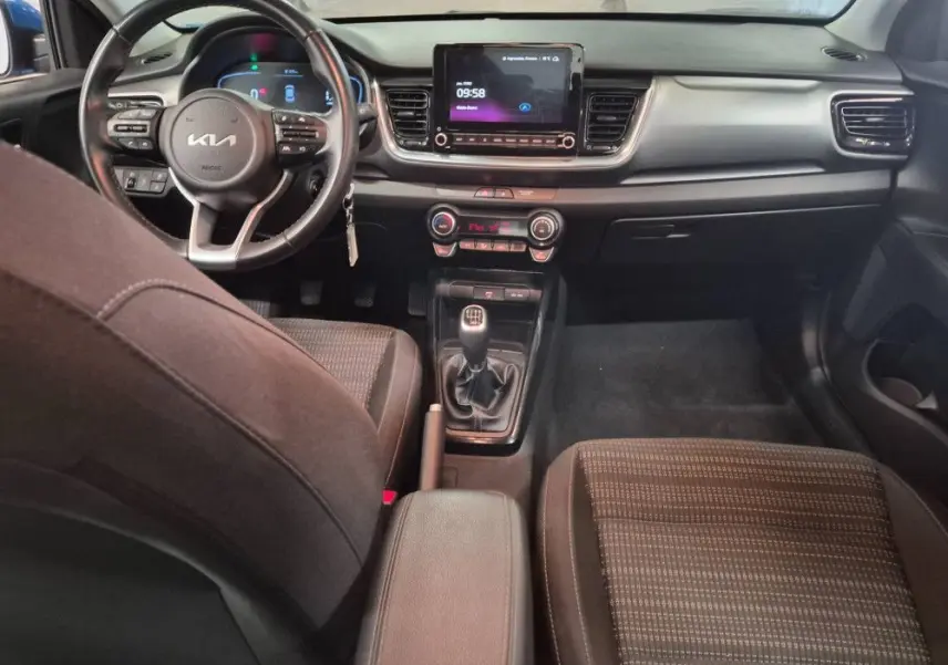 Vue intérieure du tableau de bord et console centrale du Kia Stonic bleu 2024 avec boîte manuelle et écran tactile.