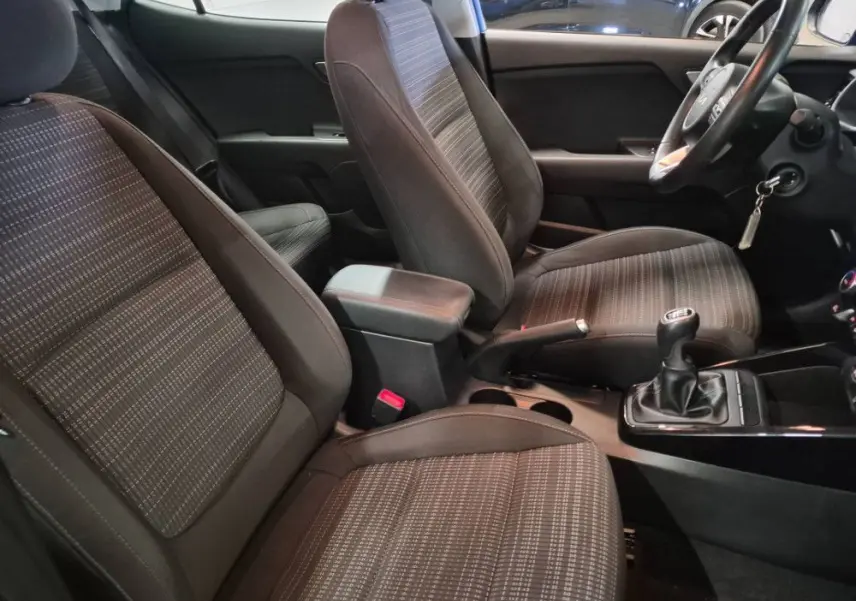 Vue intérieure côté conducteur du Kia Stonic 2024, sièges tissu gris avec boîte manuelle et volant à droite.