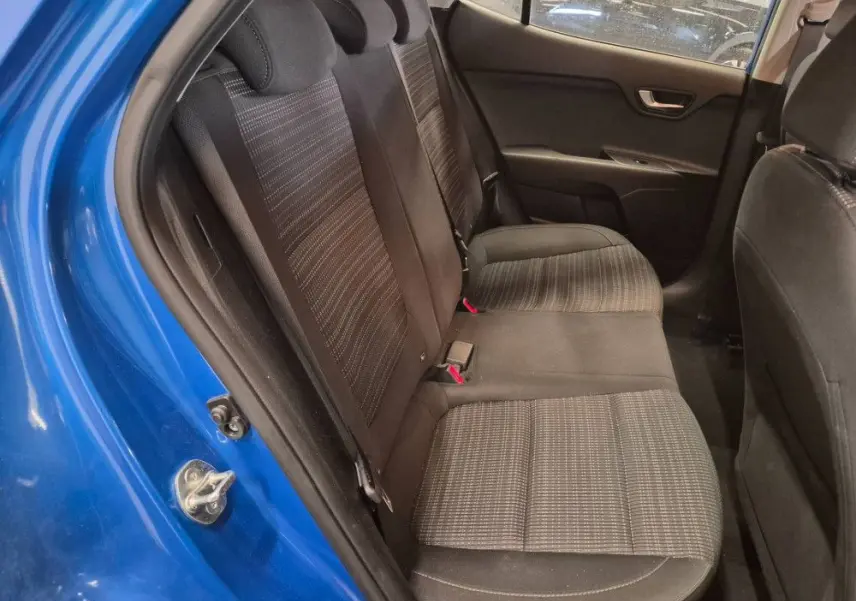 Vue intérieure des sièges arrière du KIA STONIC bleu 2024, avec tissu noir à motifs et ceinture de sécurité rouge visible.