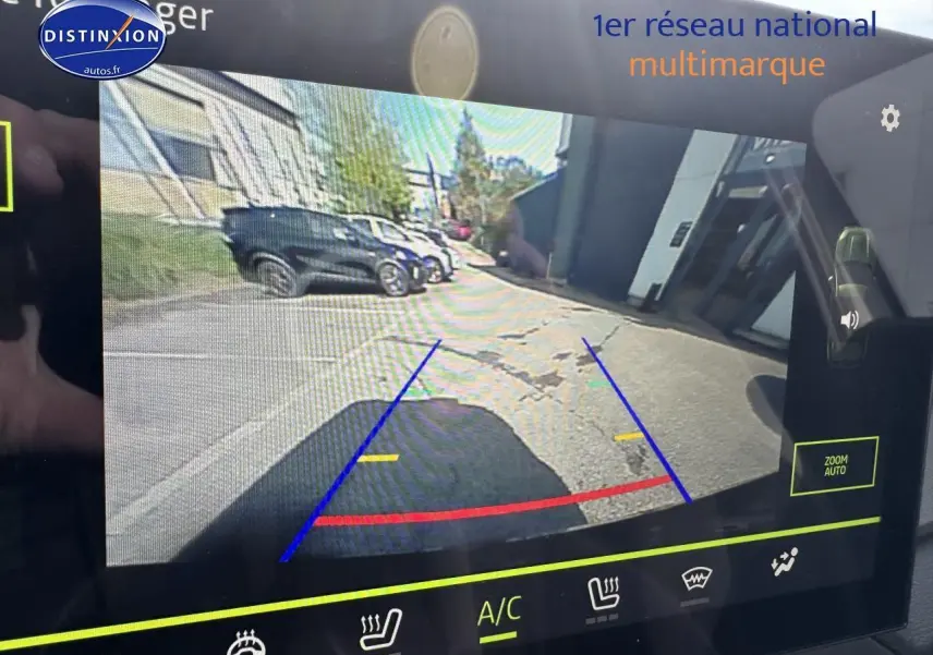 Écran tactile montrant la caméra de recul d'un Dacia Duster vert cèdre, vue arrière avec lignes de guidage colorées.