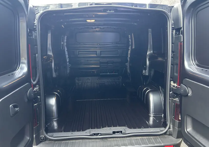 Vue arrière du Renault Trafic Fourgon gris Comète montrant l’espace de chargement vide et les portes ouvertes.