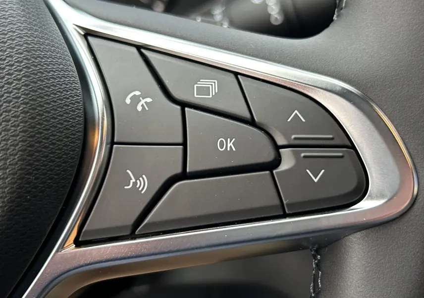 Gros plan sur les commandes multifonctions au volant du Renault Trafic Fourgon gris, avec boutons de navigation et appels.