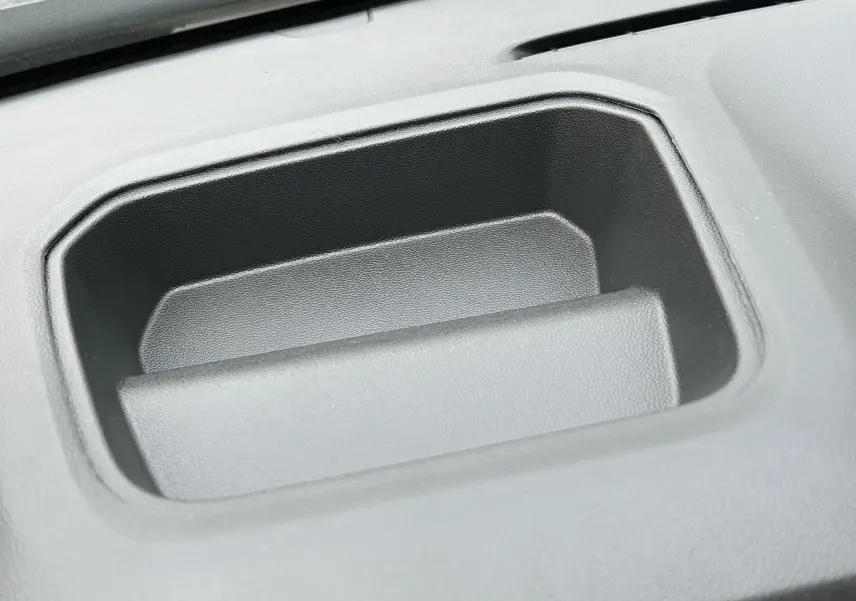 Gros plan sur un rangement en plastique noir intégré au tableau de bord du Renault Trafic Fourgon gris Comète.