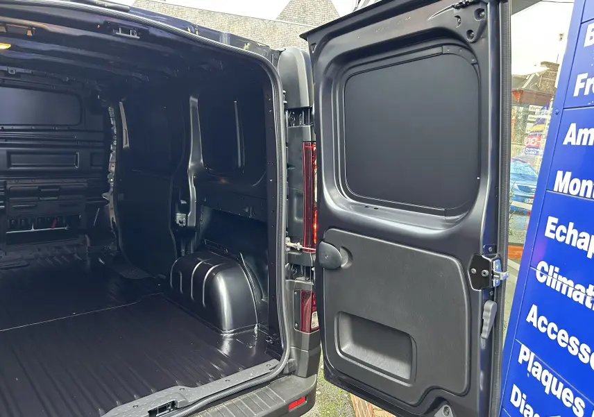 Vue arrière ouverte du Renault Trafic Fourgon gris Comète, montrant l'espace de chargement vide et la porte battante droite.