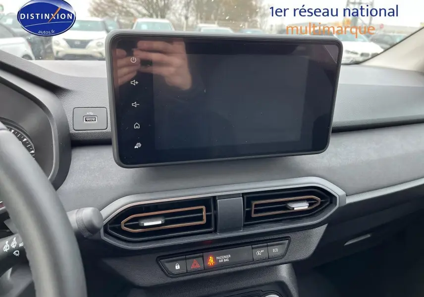 Vue intérieure du tableau de bord de la Dacia Jogger blanche 2025, avec écran tactile et aérateurs centraux noirs.