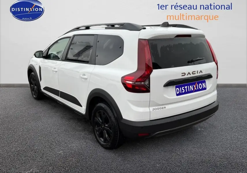Vue 3/4 arrière droite d'un Dacia Jogger blanc 7 places avec barres de toit et jantes noires.