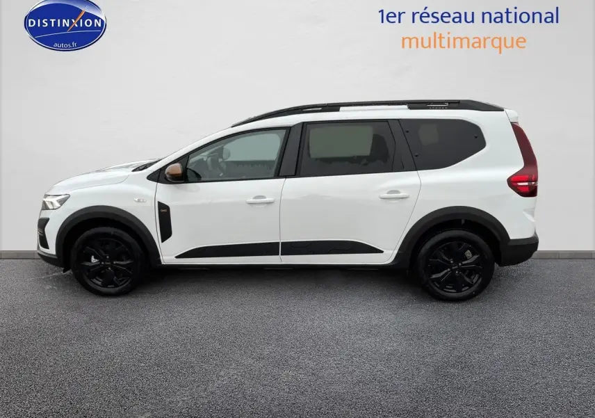 Vue de profil côté gauche d'un Dacia Jogger blanc 2025 avec jantes noires et barres de toit noires.