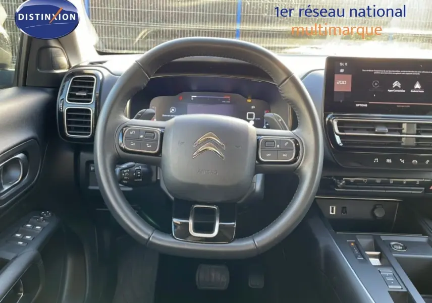 Vue intérieure centrée sur le volant noir du Citroën C5 Aircross 2025 avec tableau de bord digital et écran tactile.