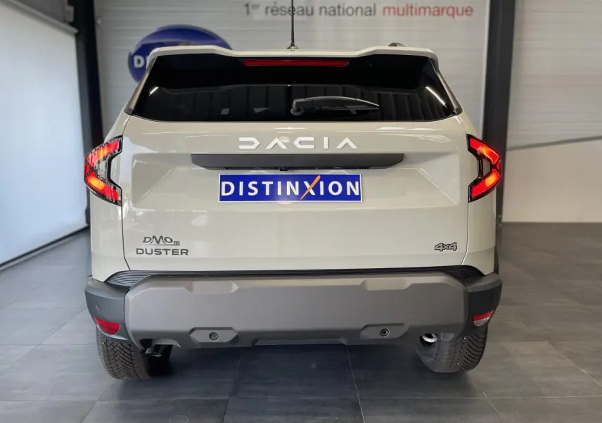 Vue arrière du SUV Dacia Duster beige 2025 avec feux LED en forme de C et logo 4x4 visible.