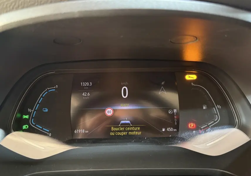 Tableau de bord numérique du Renault Captur bleu 2024, affichage multifonctions avec alertes et jauges hybrides.