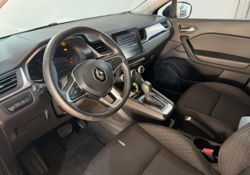 Vue intérieure côté conducteur du Renault Captur 2024, volant cuir multifonctions et écran tactile central visible.
