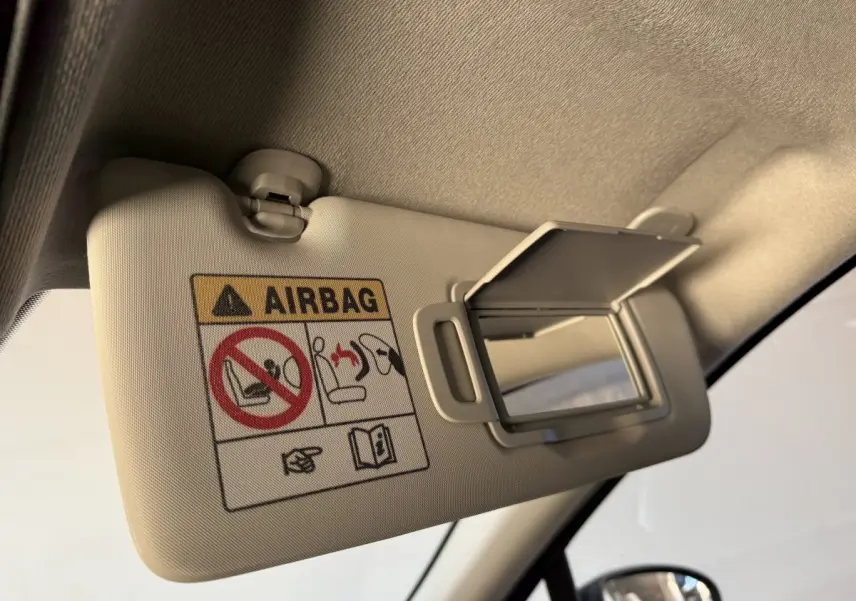 Détail du pare-soleil beige avec miroir ouvert et avertissement airbag dans un Renault Captur bleu, vue intérieure côté conducteur.