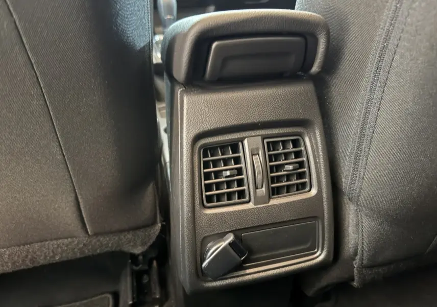 Détail des aérateurs arrière et prise 12V entre les sièges noirs du Renault Captur bleu 2024.