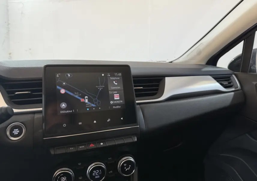 Tableau de bord intérieur du Renault Captur bleu 2024, vue centrée sur l'écran tactile et commandes climatisation.