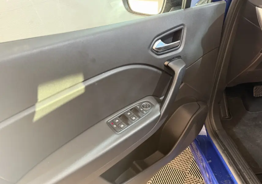 Vue rapprochée de la porte avant gauche noire du Renault Captur bleu 2024 avec commandes électriques des vitres.