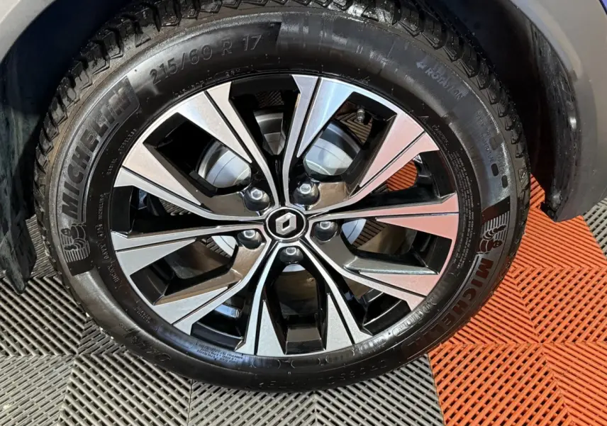 Gros plan sur la roue avant gauche du Renault Captur bleu, jante alliage bicolore avec logo Renault central.