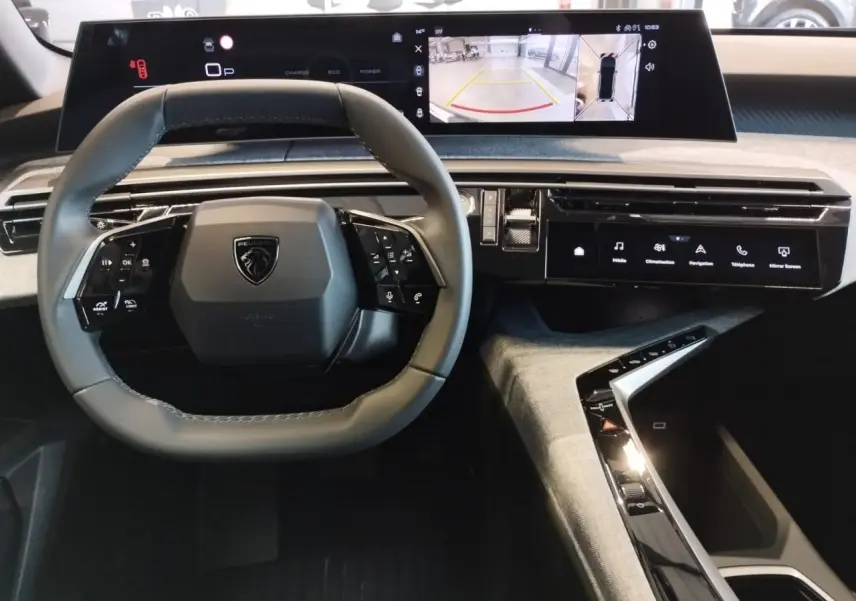 Vue intérieure du tableau de bord du Peugeot 3008 Hybrid 2025 avec volant compact et double écran incurvé flottant.
