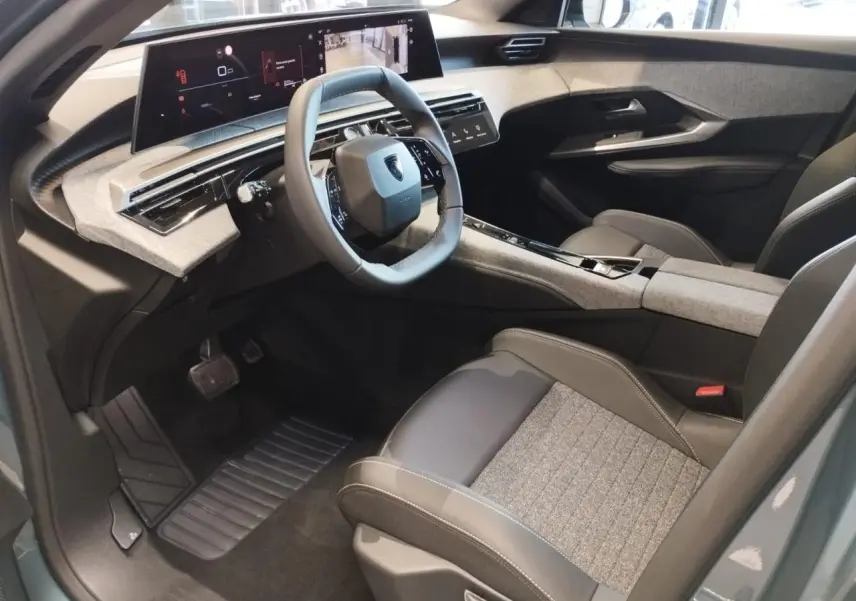 Vue intérieure côté conducteur du Peugeot 3008 hybride 2025 avec tableau de bord et écran incurvé flottant.