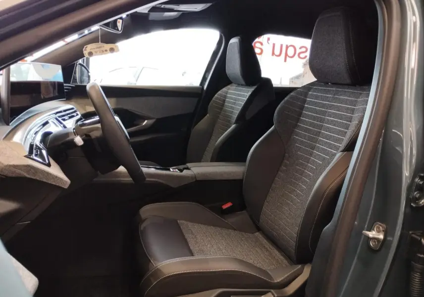 Vue intérieure côté gauche du Peugeot 3008 2025 avec sièges tissu gris et cuir noir, tableau de bord et écran incurvé flottant.