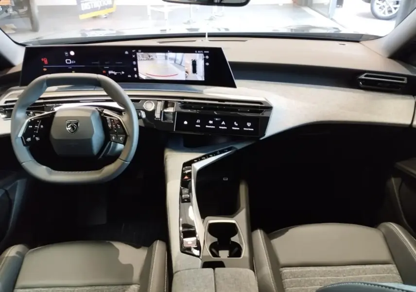 Vue intérieure avant du Peugeot 3008 2025 avec tableau de bord clair, écran incurvé flottant et volant compact noir.