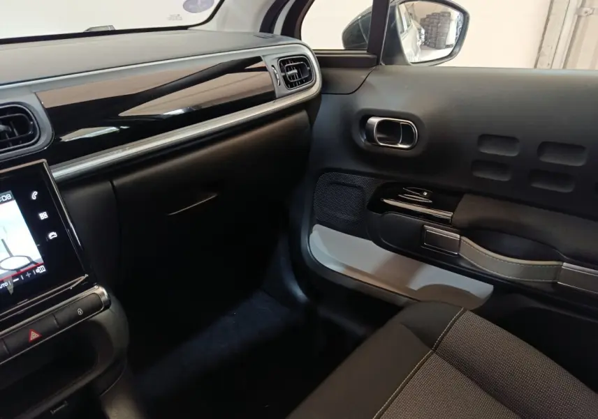 Intérieur côté passager de Citroën C3 2020, tableau de bord noir brillant et porte avec poignée design grise.