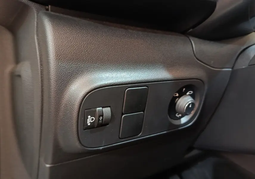 Gros plan sur les commandes noires de réglage des phares et des rétroviseurs dans l'habitacle d'une Citroën C3.