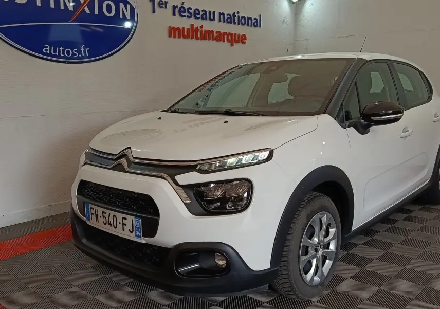 Citroën C3 blanche vue 3/4 avant droit en intérieur, avec phares LED et rétroviseurs noirs ton caisse.