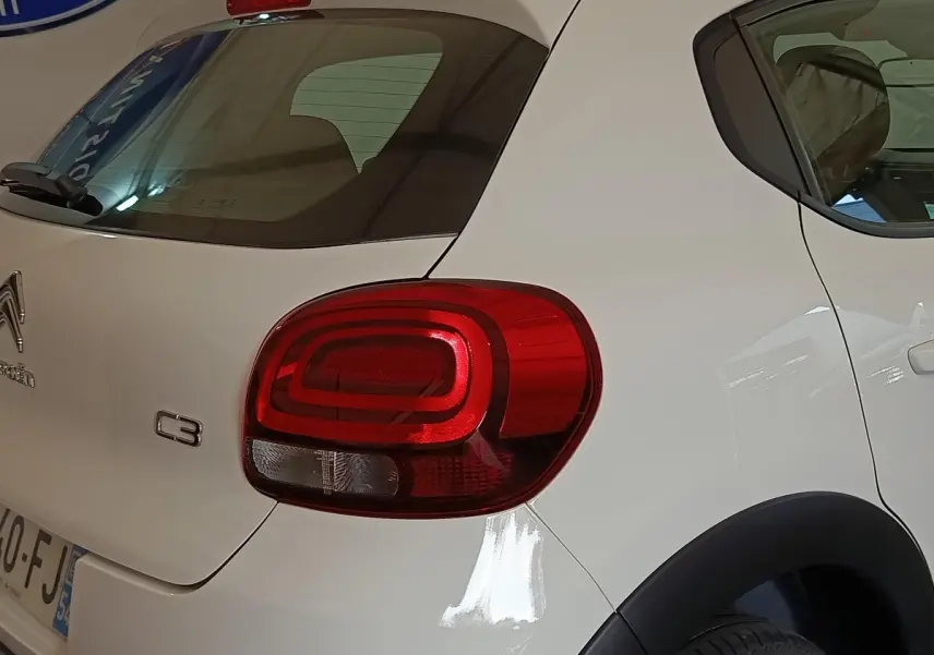 Vue 3/4 arrière droite d'une Citroën C3 blanche avec feux arrière rouges et logo C3 visible sur la malle.