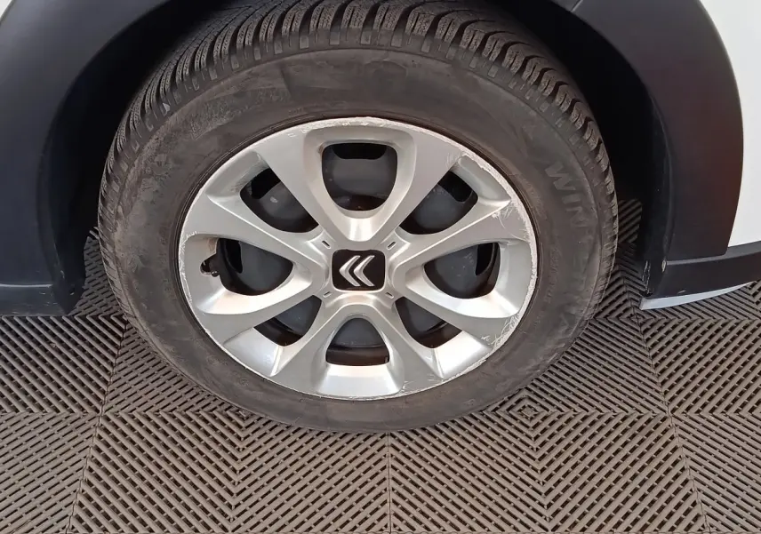 Gros plan sur la roue avant gauche d'une Citroën C3 blanche, avec jante alliage et logo Citroën central.