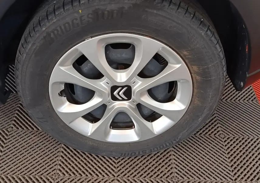 Gros plan sur la roue avant gauche d'une Citroën C3 blanche avec jante argentée et logo Citroën au centre.