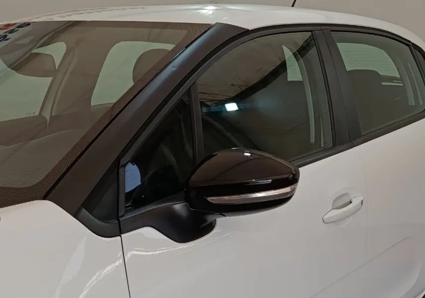 Vue rapprochée du côté gauche d'une Citroën C3 blanche 2020 avec rétroviseur noir et poignée de porte visible.