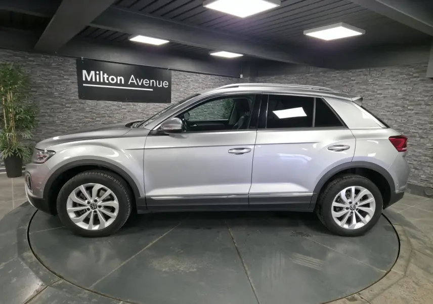 Vue latérale droite du Volkswagen T-Roc gris métallisé 2022 avec jantes alliage 17 pouces en showroom.