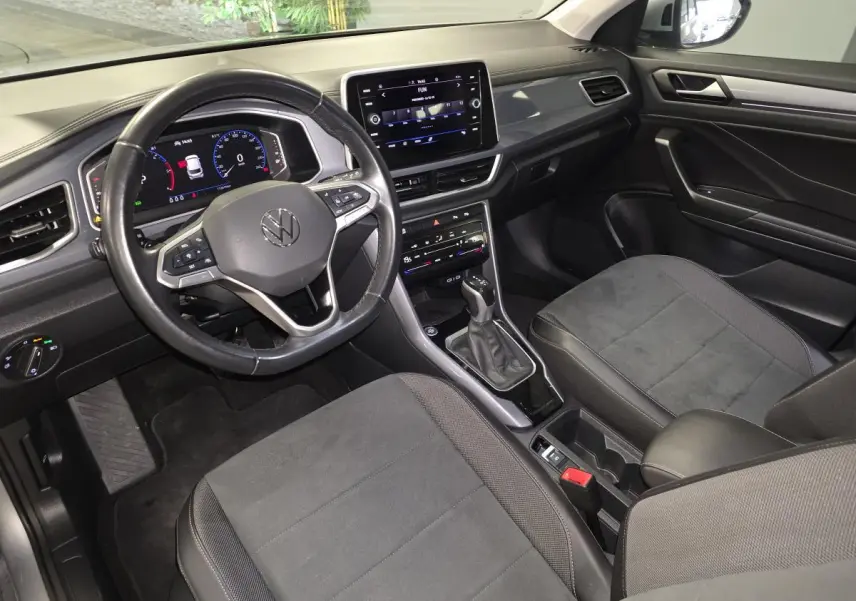 Vue intérieure avant droite du Volkswagen T-Roc 2022 avec sellerie noire, volant multifonction et écran tactile central.