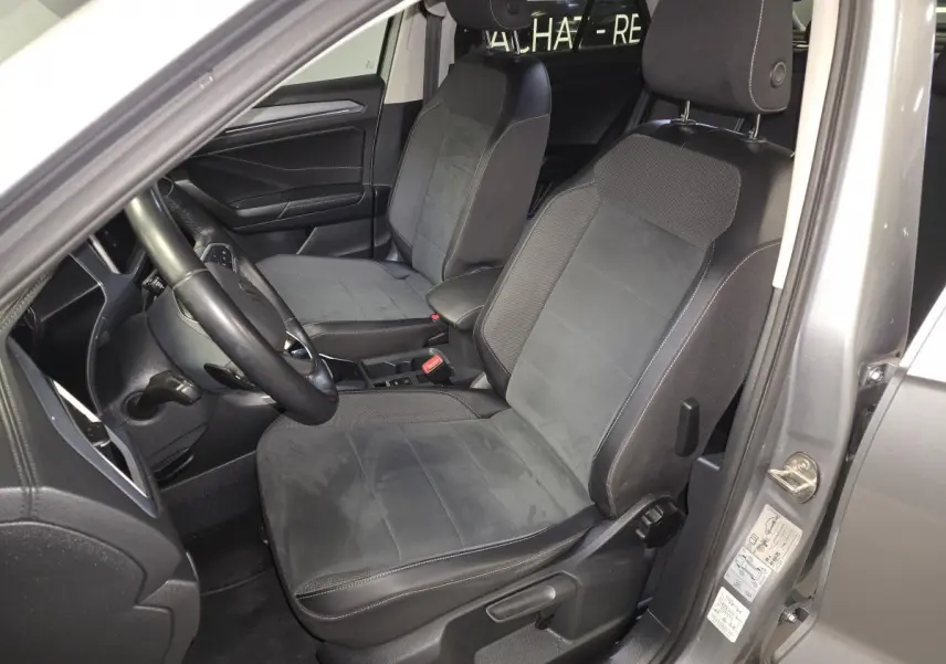 Vue intérieure côté conducteur du Volkswagen T-Roc gris 2022, mettant en valeur les sièges en sellerie Artvelours noir.