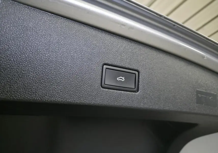 Bouton d'ouverture électrique du hayon sur la face intérieure du coffre d'un Volkswagen T-Roc gris.