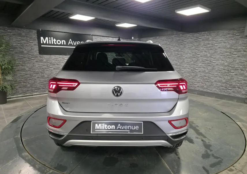 Vue arrière d'un Volkswagen T-Roc gris métallisé 2022 avec feux LED allumés dans un showroom.