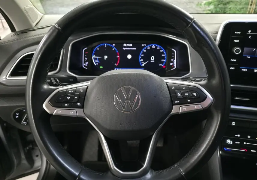 Vue rapprochée du volant en cuir noir avec commandes multifonctions d'un Volkswagen T-Roc 2022, tableau de bord digital visible.