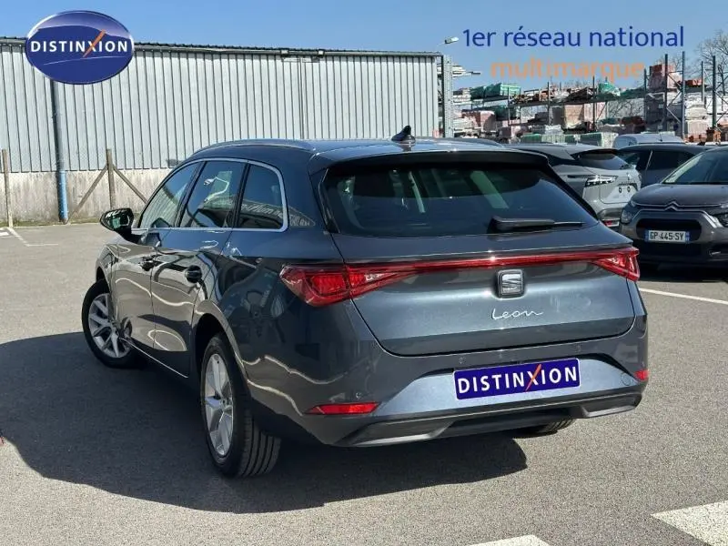 SEAT LEON ST gris magnétique métallisé vu en 3/4 arrière droit, avec feux arrière reliés par une bande lumineuse rouge.