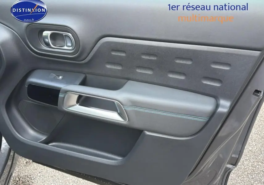 Gros plan sur la porte avant droite gris platinium du Citroën C5 Aircross avec poignée argentée et surpiqûres bleues.