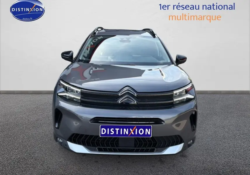 Vue frontale d'un Citroën C5 Aircross gris platinium 2025 avec calandre distinctive et barres de toit visibles.
