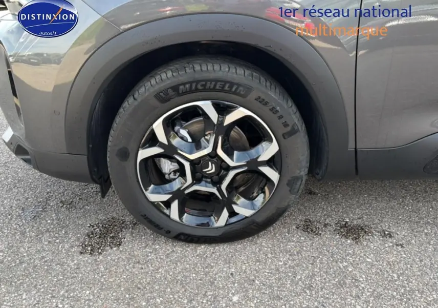 Gros plan sur la roue avant droite avec jante alu noire et grise du Citroën C5 Aircross gris platinium.