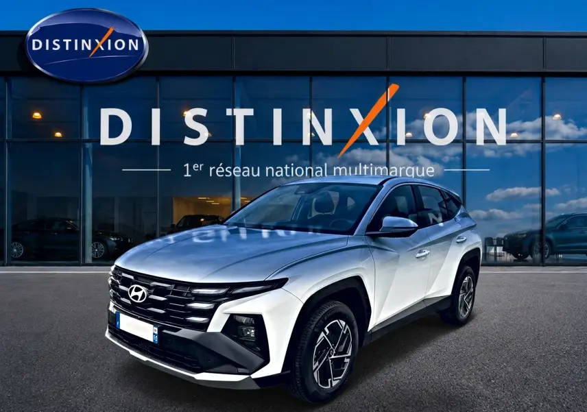 Hyundai Tucson blanc en 3/4 avant droit, avec calandre noire distinctive et jantes alliage 17 pouces.