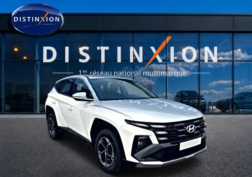 Hyundai Tucson blanc vu en 3/4 avant droit, avec calandre noire et jantes alliage 17 pouces devant showroom Distinxion.