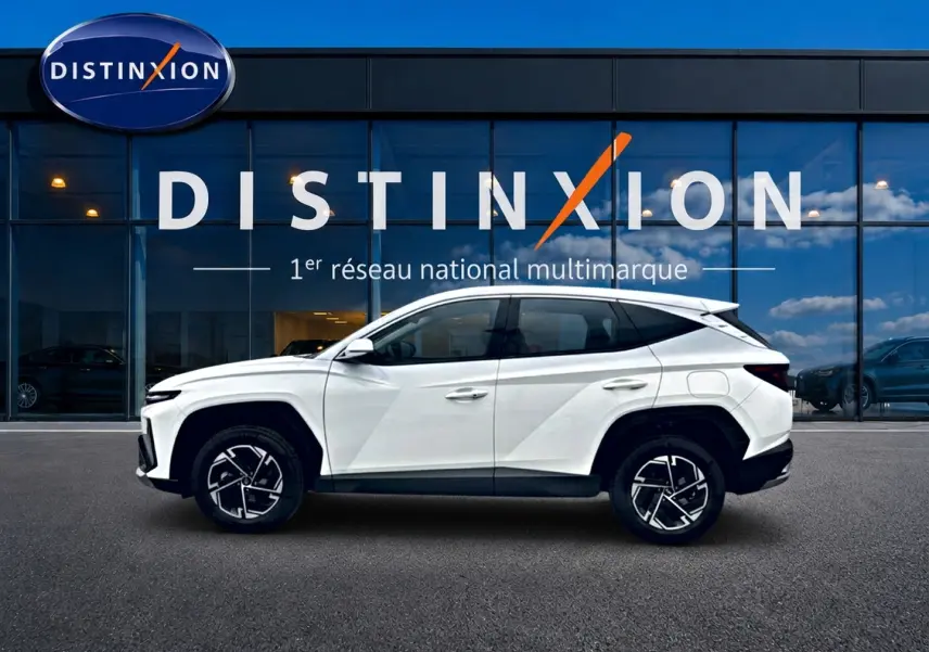 Vue de profil côté gauche du Hyundai Tucson blanc 2026 devant une vitrine avec logo Distinxion.