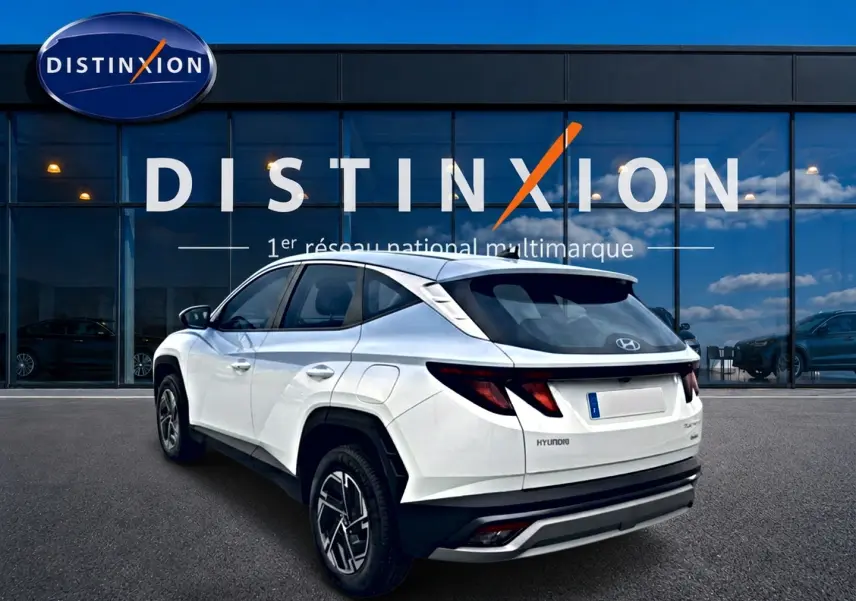 Vue 3/4 arrière droite du Hyundai Tucson blanc hybride 2026, avec jantes alliage et feux arrière LED distinctifs.