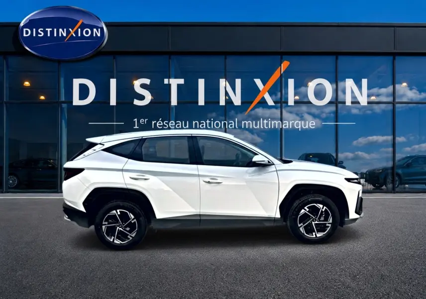 Profil latéral gauche d'un Hyundai Tucson blanc 2026 avec jantes alliage et lignes anguleuses modernes.