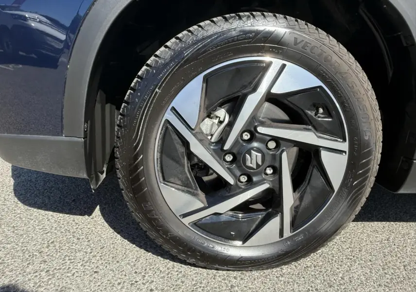 Gros plan sur la roue avant gauche du Suzuki Vitara 2025 bleu foncé, mettant en valeur la jante alliage au design moderne.