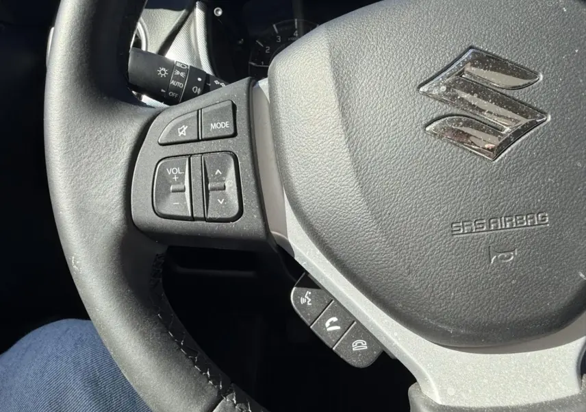 Vue rapprochée du volant noir du Suzuki Vitara 2025, avec commandes audio et logo Suzuki argenté visible.