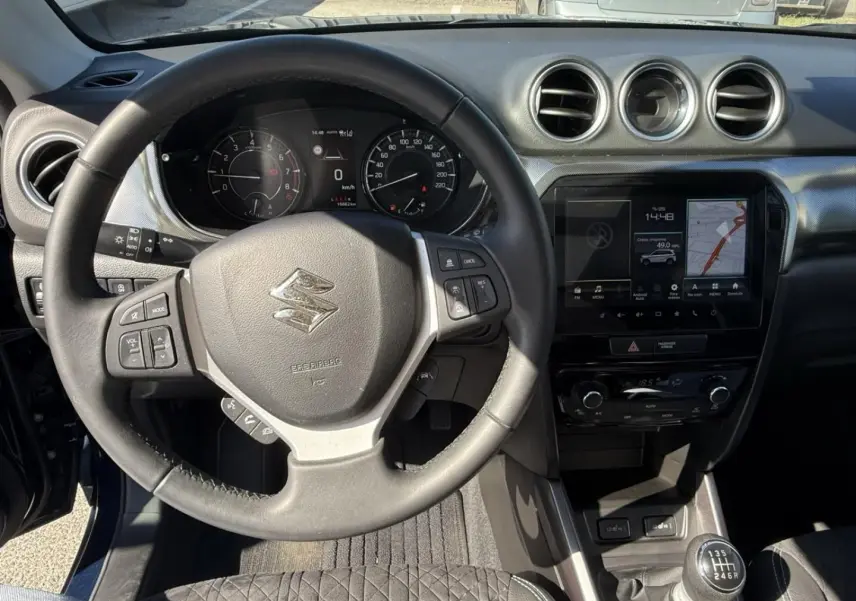 Vue intérieure centrée sur le volant et la console centrale du Suzuki Vitara 2025, avec boîte manuelle et écran tactile.