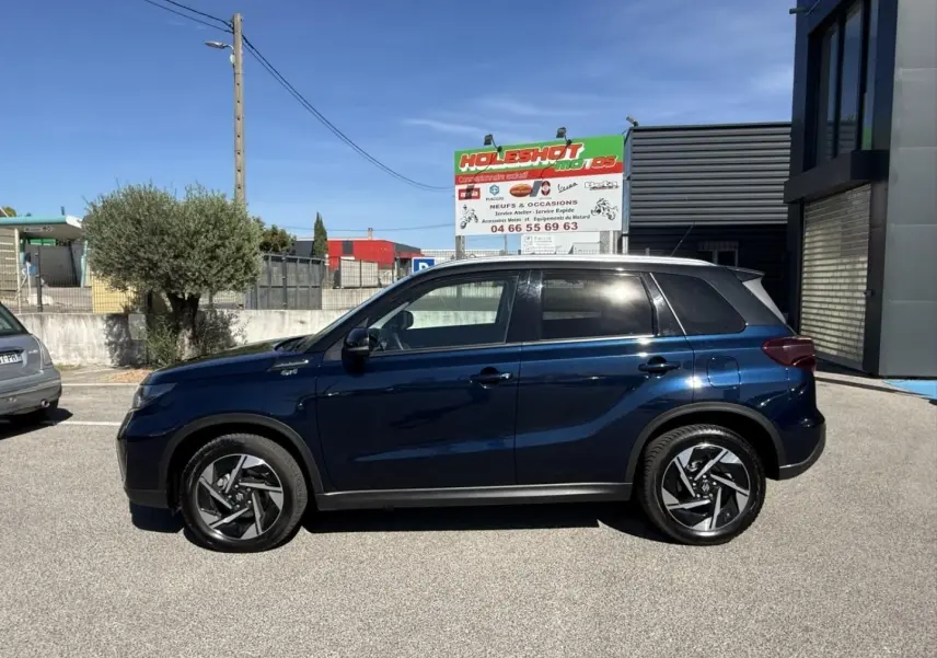 Suzuki Vitara 2025 bleu foncé métal vu de profil côté gauche, avec toit noir et jantes alliage distinctives.